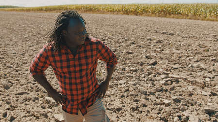 Young african farmer standing on the agricultural plowed land . High quality photoの写真素材