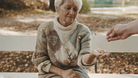 Old poor woman getting some coins from passenger. High quality photoの写真素材