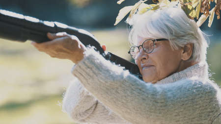 Elderly gray haired woman holding a gun in her hands. War or revolution concept. High quality photoの写真素材