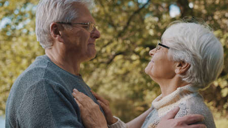 Happy old enjoying day in park. Senior man flirting with elderly woman. Dance in autumn day. High...