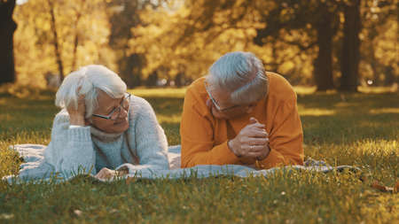 Wellbeing concept. Portrait of happy senior retired couple relaxing in autumn park. High quality...