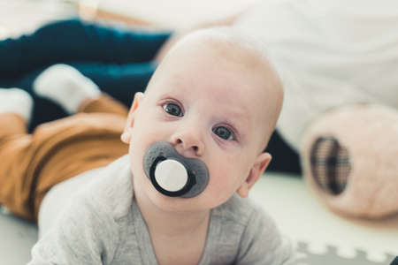 Tummy time. Cute newborn baby with big blue eyes and pacifier looking at camera. High quality photoの写真素材
