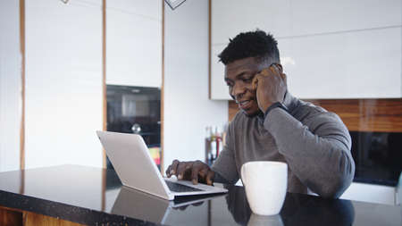working remotely. African american black businessman having phone call in his appartment while...