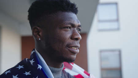 Black man african-american with USA flag covering his shoulders. High quality photoの写真素材