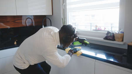 Black man cleaning kitchen. Germaphobe excessively wiping reflective surface. High quality photo