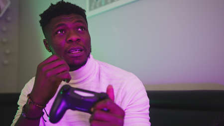 Portrait of happy black man playing game using video game console controlling joystick and winning....