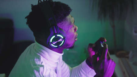 Portrait of happy black man playing game using video game console controlling joystick and winning....