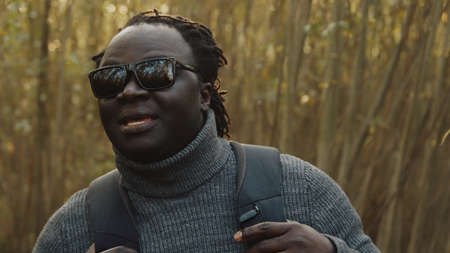 Young african american black man traveler with backpack walking through the forest. High quality...