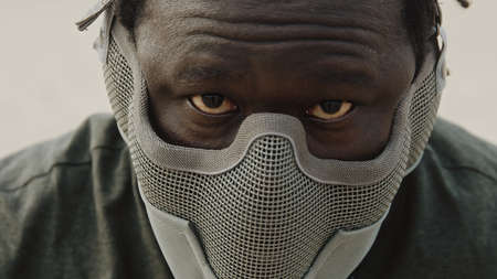 Close up, african man with mask over his face and red eyes. Scary warrior. High quality photo