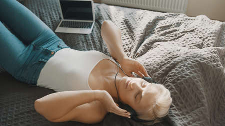 Young happy woman listening to the music on headphones in her bedroom. High quality photo
