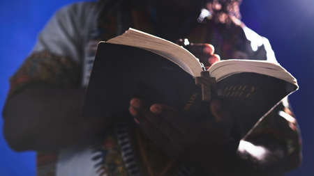 Unrecognizable African black man in traditional dress with rosary reading the Holy Bible . High quality photoの写真素材