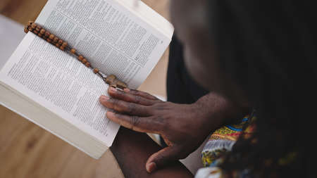 Unrecognizable African black man in traditional dress with rosary reading the Holy Bible . High quality photoの写真素材