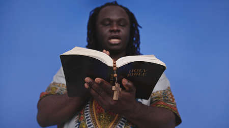 Portrait of african black man in traditional dress with rosary reading the Holy Bible . High quality...