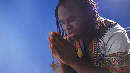 african black man in traditional dress praying with rosary. High quality photo