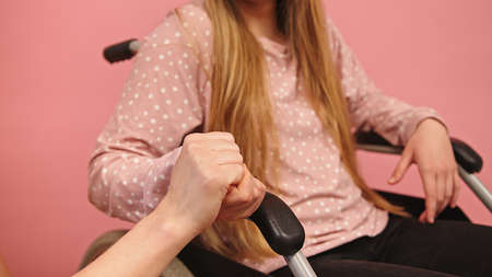 Caregiver holding hand of young disabled woman in the wheelchair. High quality photoの写真素材