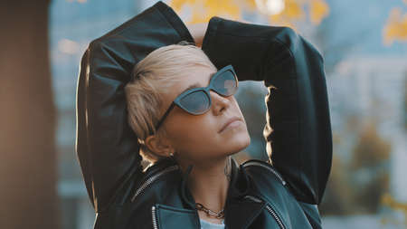 Close up portrait of joyful young woman with bright hair and sunglasses standing with hands over the...