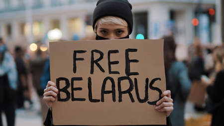 Young woman with face mask holding banner with writtings - free belarus. High quality photo