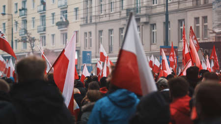 Warsaw, Poland 11.11.2020 - Independence day march on 102nd anniversary in Warsaw. Crowd of people marching with polish flags and red flares . High quality photoのeditorial素材