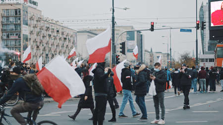 Warsaw, Poland 11.11.2020 - Independence day march on 102nd anniversary in Warsaw. Crowd of people marching with polish flags and red flares . High quality photoのeditorial素材
