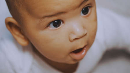 Beautiful mulatto baby having tummy time. Father touching his chin. High quality photoの写真素材