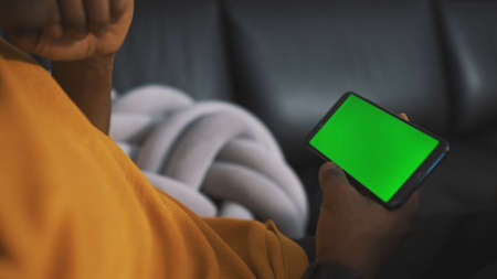 Close up smartphone with green screen in the hands of unrecognizable african american black man....