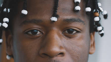 Close up, eyes of confident african american black man with braided hear looking into the camera....