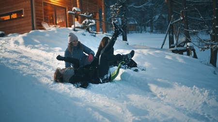 Best female friends having fun and sliding on the sleds on beautiful winter evening. High quality...