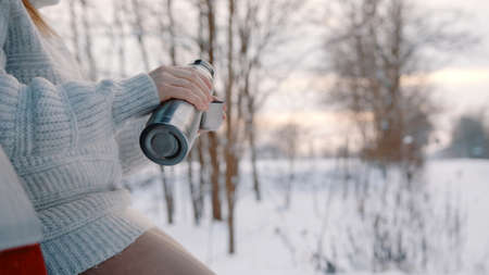 Close up, pouring the coffee in the cup from the thermal bottle while resting outside on the snowy day. High quality photoの写真素材