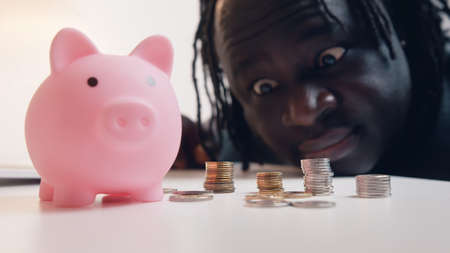 Man counting his savings. Close up of piggybank surrounded by coins. Investing decision. High...