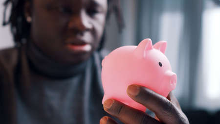 Upset poor african american black man holding empty piggy bank. High quality photo