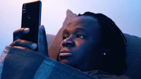 African american black man holding smartphone while resting on the couch. High quality photo