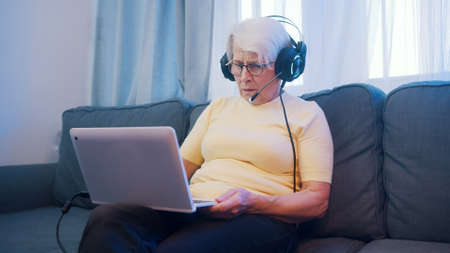Elderly woman with headset having video call with family. Old people and technology. High quality photoの写真素材