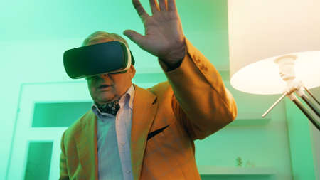 Elderly man, pensioner laughing with VR headset. High quality photo