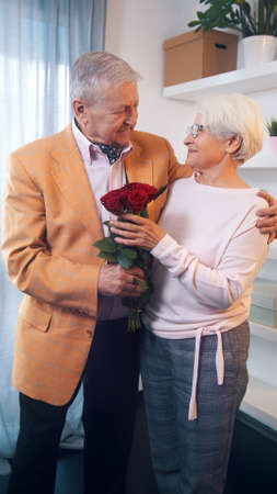 Love and happines. Elderly man giving red roses to his wife on womens day. High quality photoの写真素材