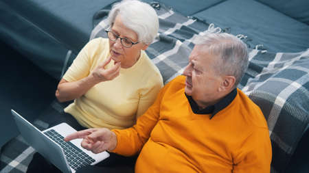 Elderly retired couple using laptop indoors. High quality photoの写真素材