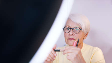 Elderly woman applying make up in the office. High quality photoの写真素材