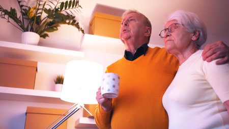 Elderly couple hugging and speaking on the phone while watching tv. . High quality photo