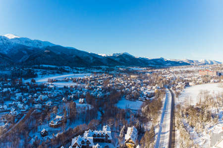 Winter season in Zakopane, Poland. Snow covered houses roads and forest with mountains in the background. High quality photoの写真素材