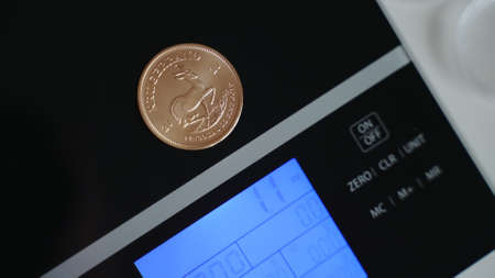 Close-up of single bronze color coin laying on electronic digital scales. Money, finance and economy...