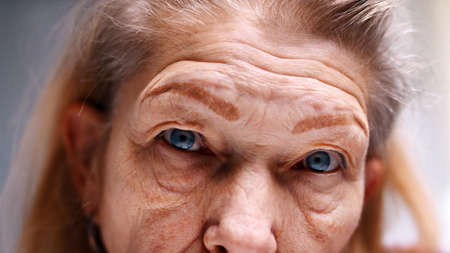 Close up on blue eyes of an elderly woman with wrinkled skin. Depression at old age. High quality photoの写真素材