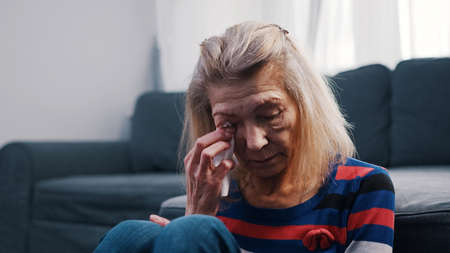 Lonely elderly woman wiping tears with tissue. Loneliness at old age. High quality photoの写真素材