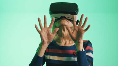 Old caucasian woman with VR headset touching the air. High quality photoの写真素材