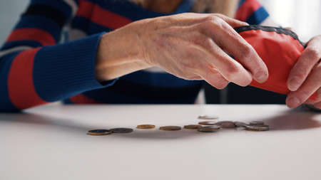 Elderly person putting money into her wallet. Poor woman running out of money. High quality photo