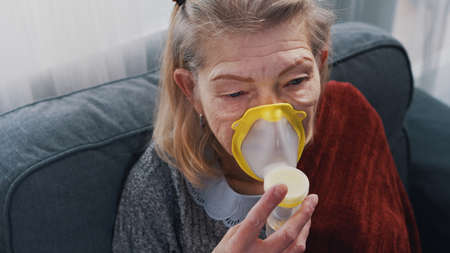 Sick old woman inhaling oxygen at home. High quality photoの写真素材