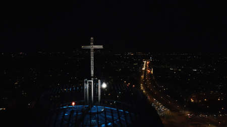 Warsaw, Poland 12.01.2020 - City at night. Closeup of cross at Church building. The nightlife of Warsaw. Busy street with vehicles running. The jet-black sky in the background.のeditorial素材