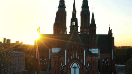 Warsaw, Poland 12.01.2020 - Facade of a Church. Sun rays shine through the old building. The shot is taken during sunset. Buildings in the background against a clear white sky.のeditorial素材
