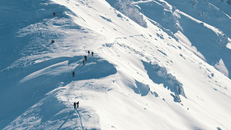 Group of hikers on a snowy landscape moving towards the peak of the mountain. High quality photo