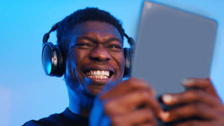 African american black man with headphones making intense face expressions while using tablet. High quality photoの写真素材