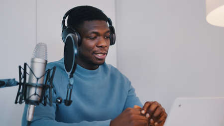 Man wearing headphones recording a video podcast using a laptop and microphone. High quality photoの写真素材
