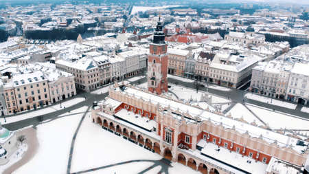 Krakows Town Hall Tower in the Main Market Square surrounded by historical buildings covered with snow. City with ancient architecture. Panoramic view of the city skyline.の写真素材